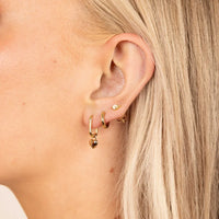 A pair of heart-shaped gold hoop charms against a white background