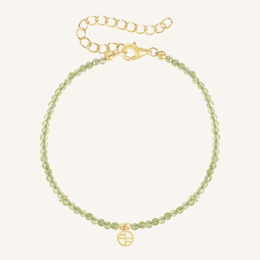 A beaded bracelet with green stones and a gold metal clasp, representing the August birthstone.