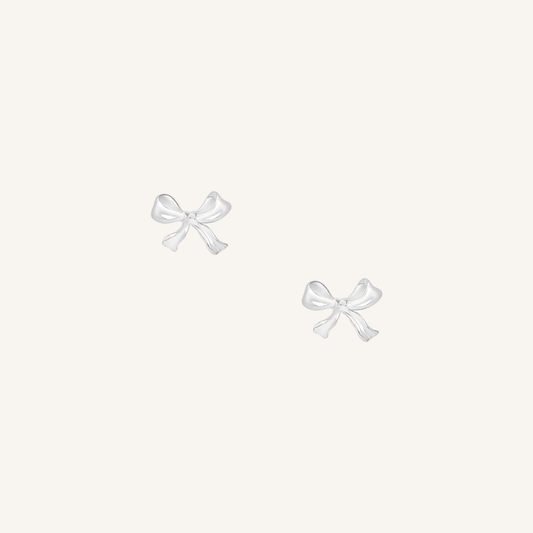 A pair of silver bow stud earrings on a white background
