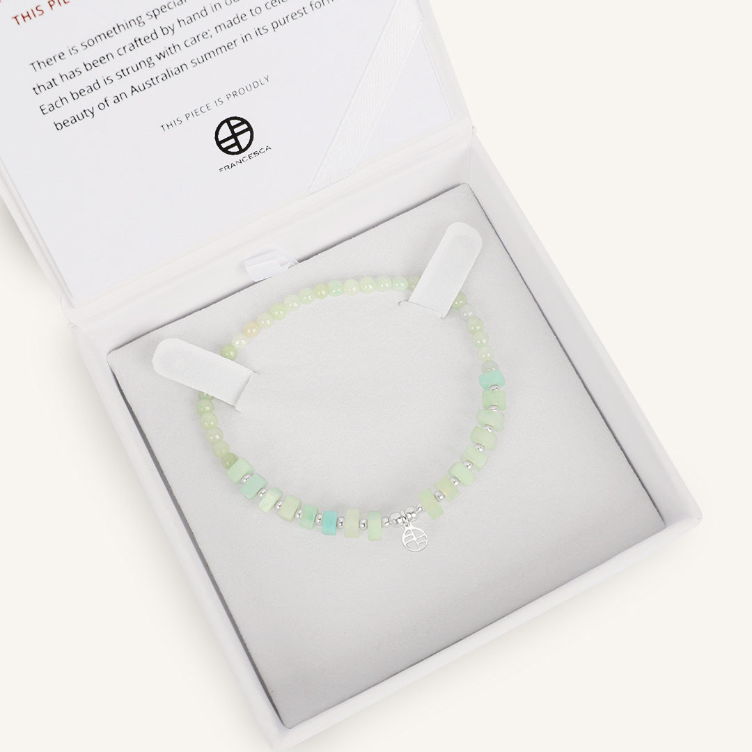 Bracelet with light green beads and gold accents, in white box 