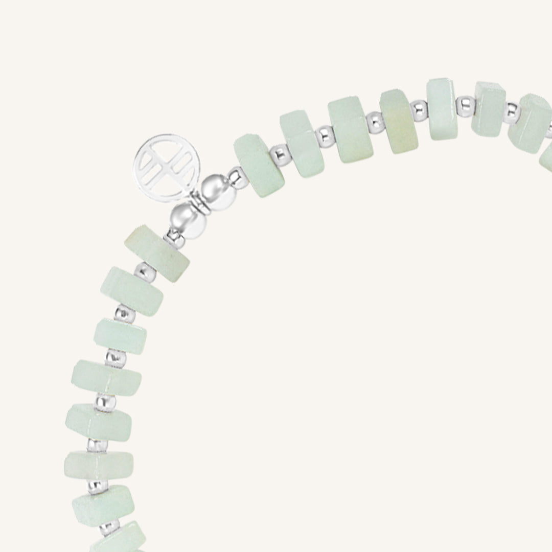 Bracelet with light green beads and silver accents on a white background