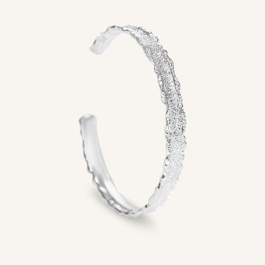 Silver bracelet with textured design on a white background