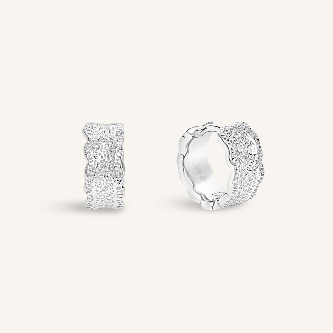 Silver hoop earrings on a light gray background