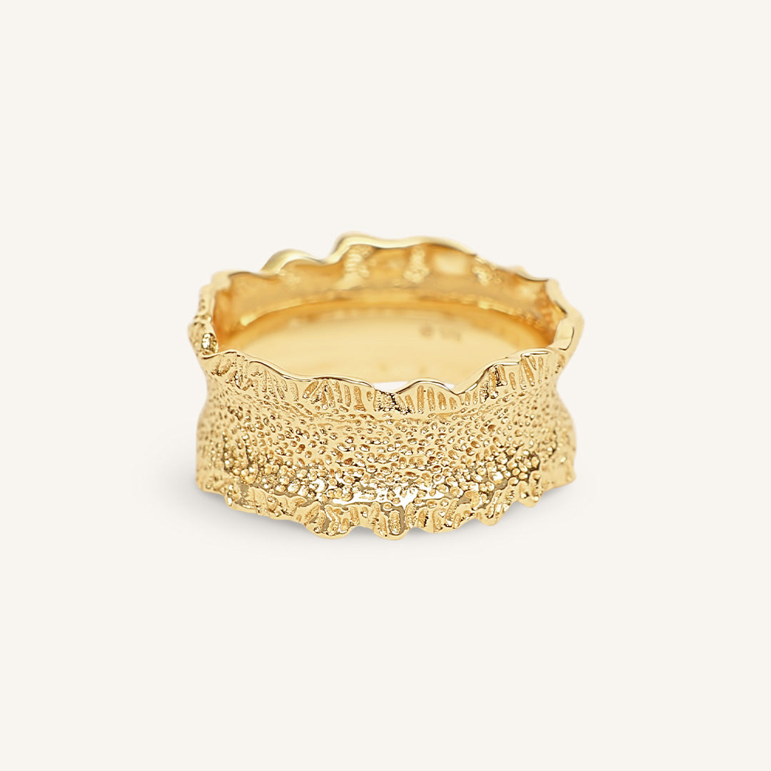 Gold ring with textured design on a white background