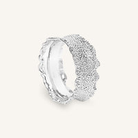 Silver ring with textured design on a white background