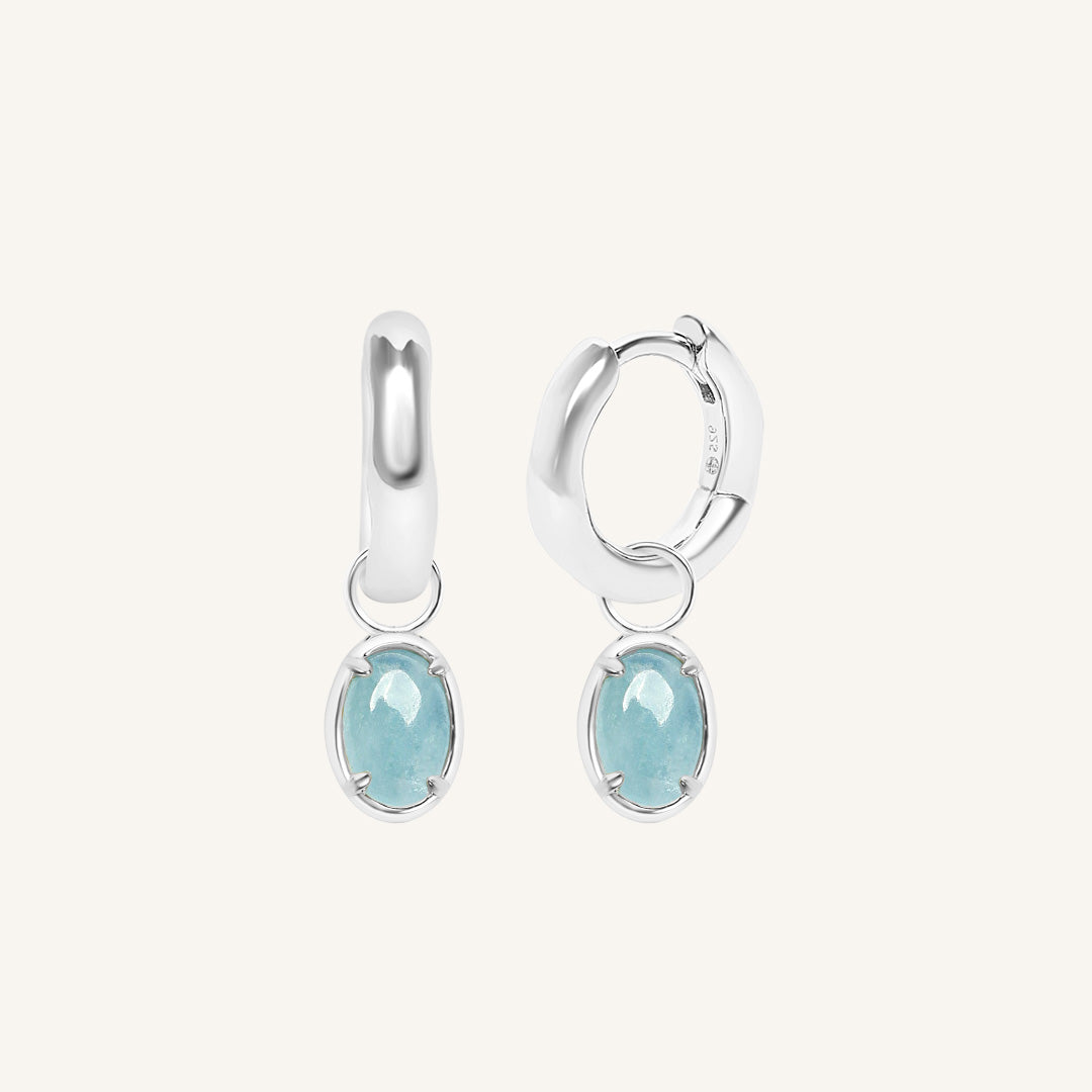 Silver earrings with light blue gemstones on a white background
