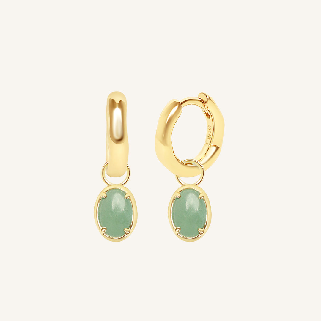 Gold hoop earrings with green gemstones on a white background