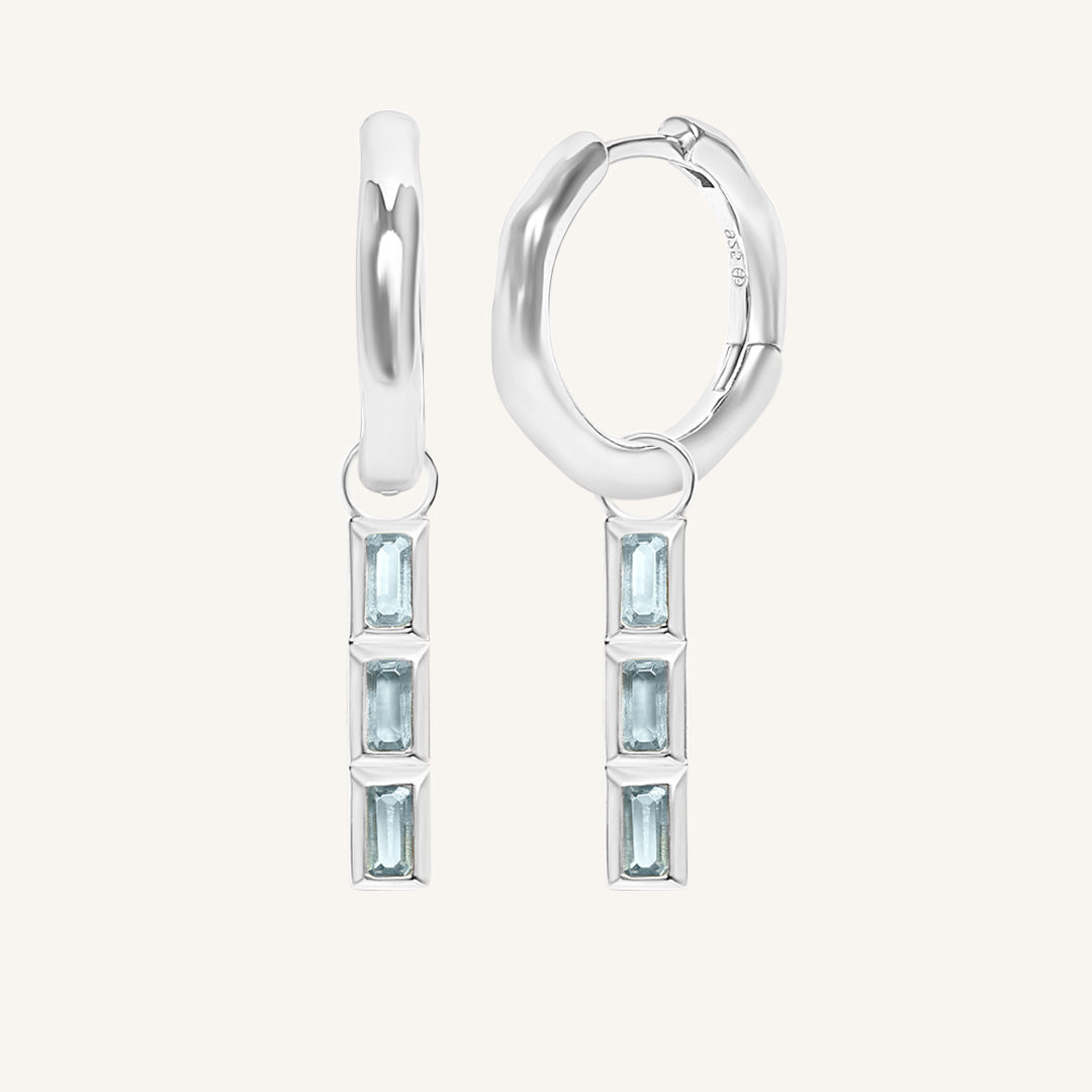 Silver hoop earrings with blue gemstones on a white background