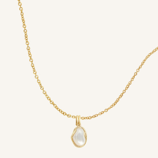 Gold necklace with a teardrop-shaped pendant on a light beige background