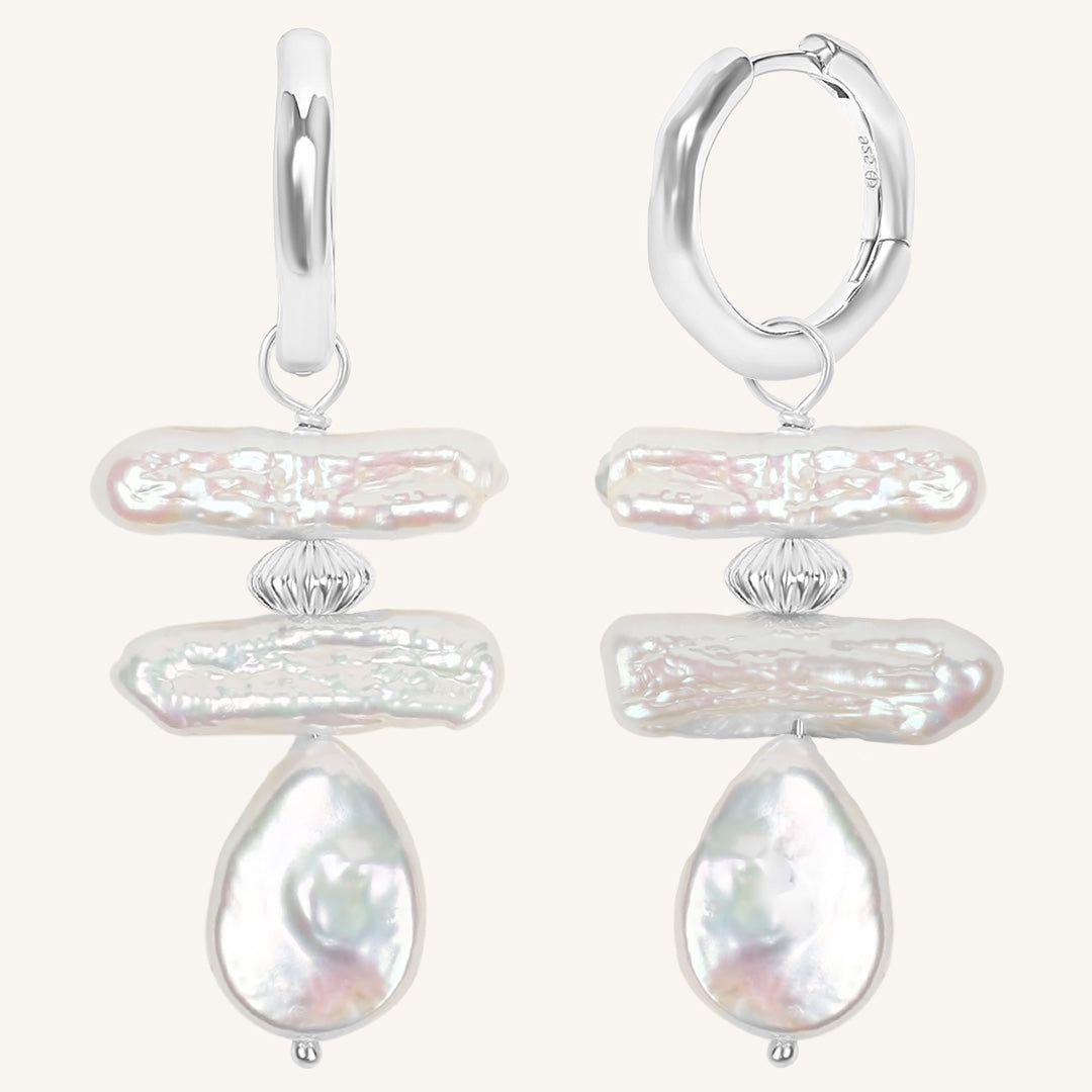 Pair of silver hoop earrings with teardrop-shaped pearls on a white background