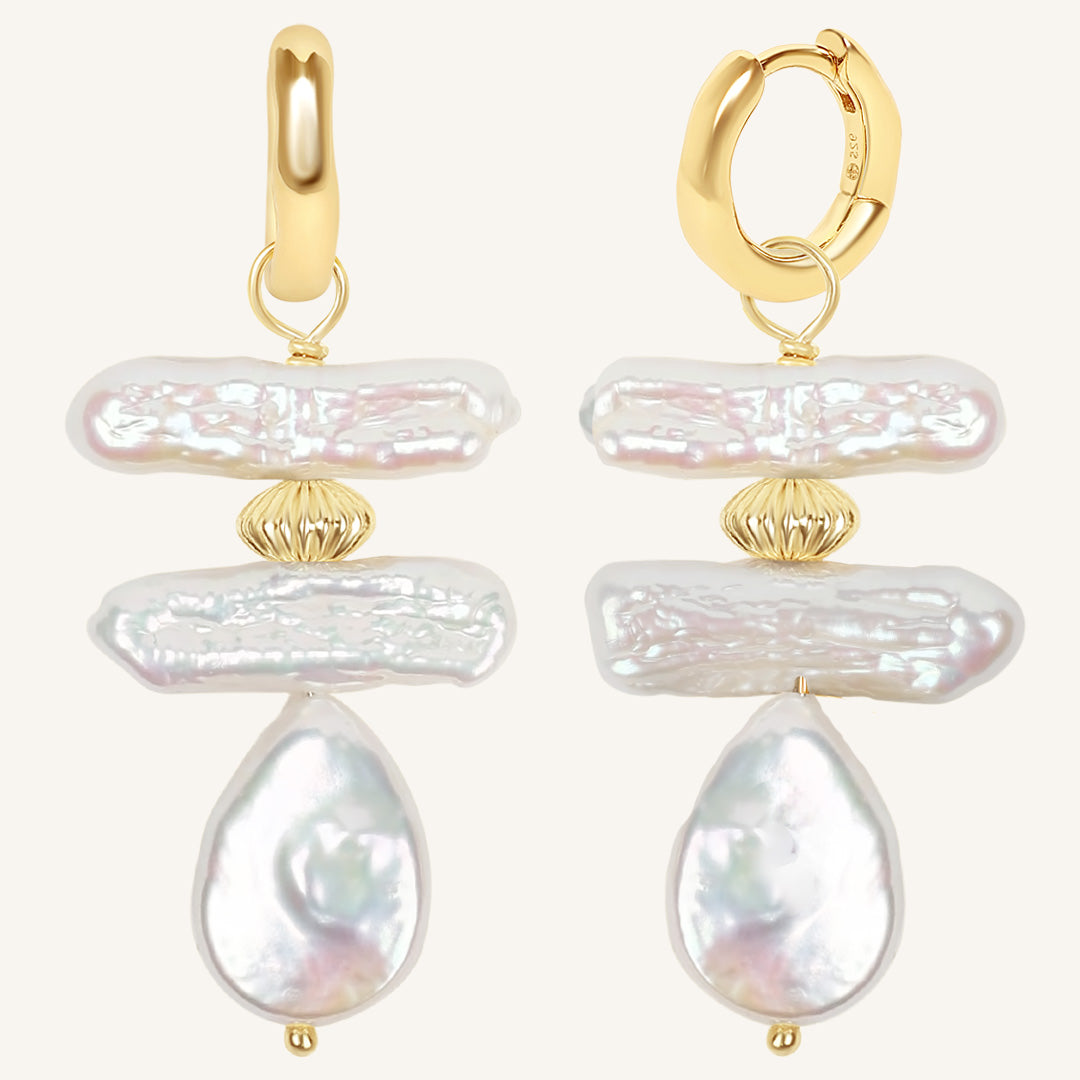 Gold hoop earrings with large pearl-like stones on a white background