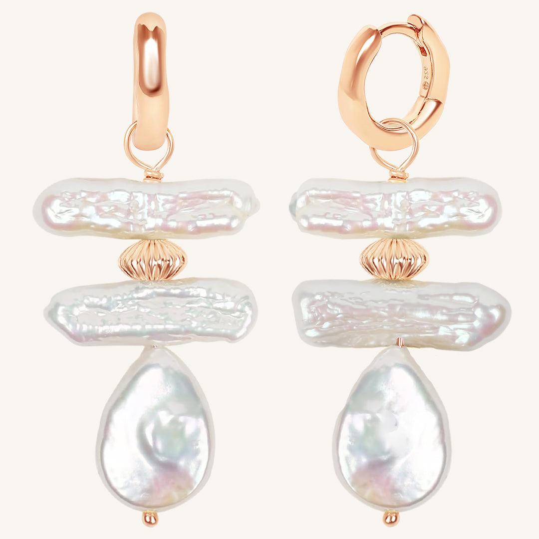 Pair of pearl earrings with rose gold accents on a white background