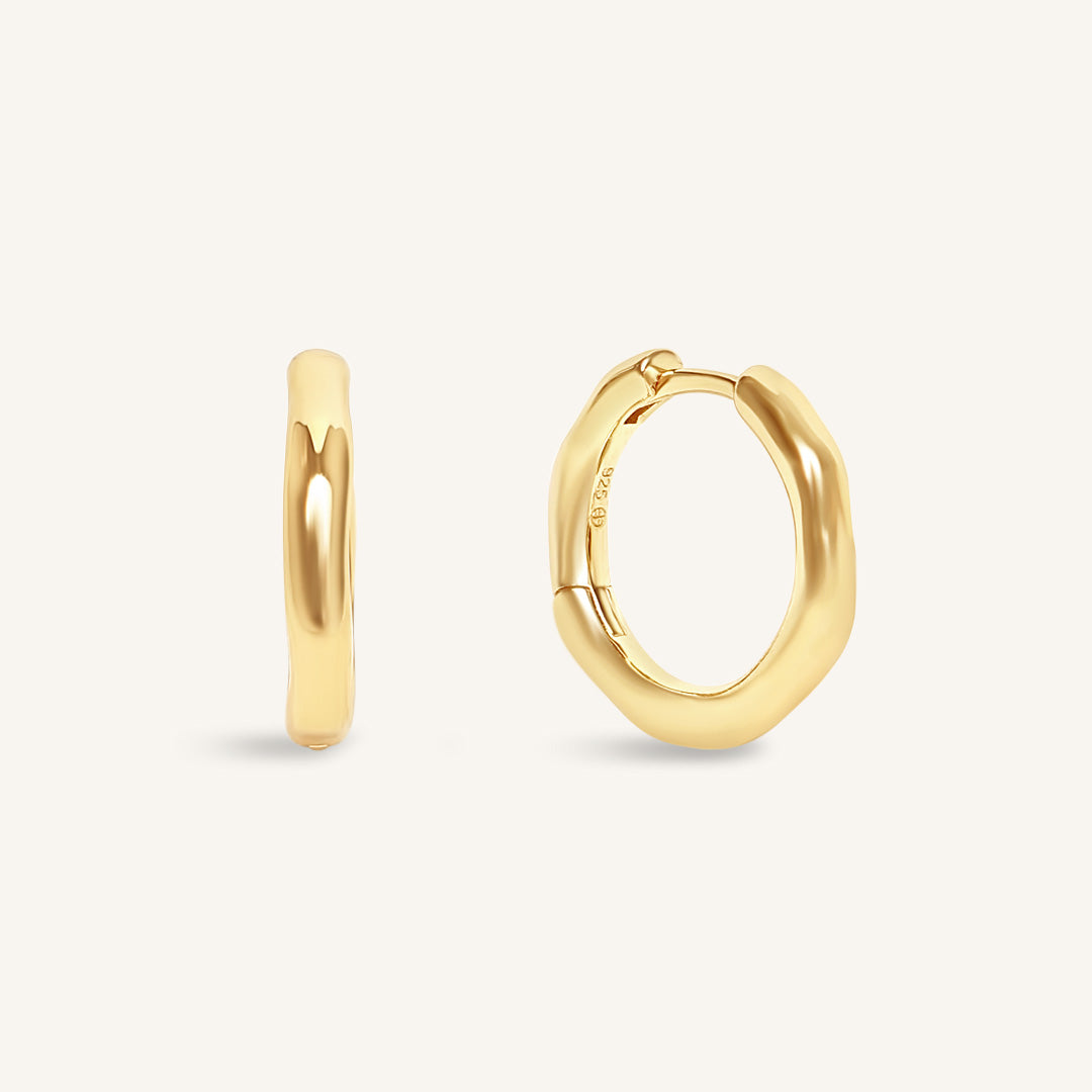 Gold hoop earrings on a light beige background