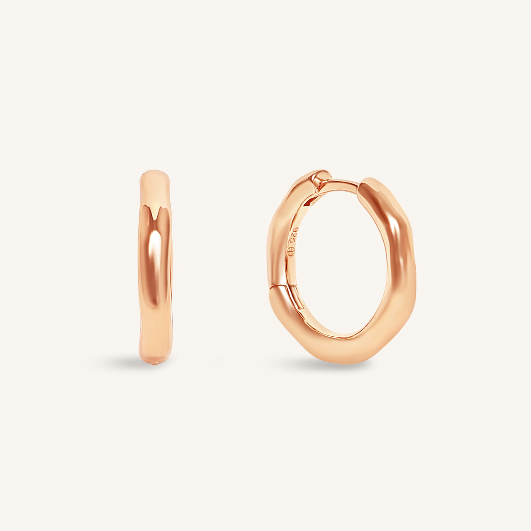 Rose gold hoop earrings on a light beige background