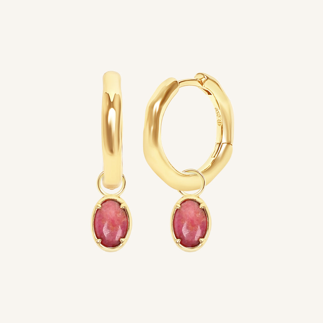 Gold hoop earrings with pink gemstones on a white background