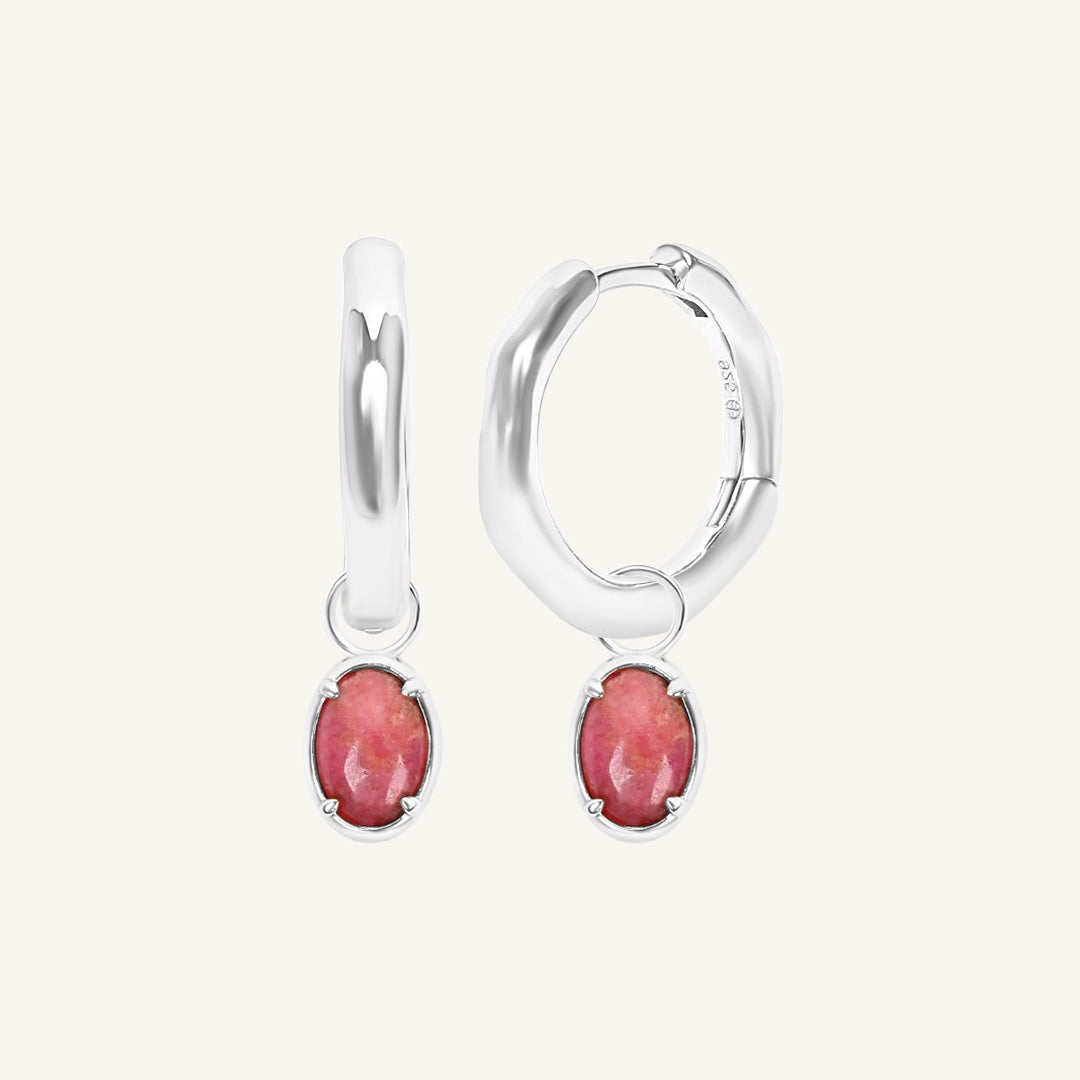 Silver hoop earrings with pink gemstones on a white background