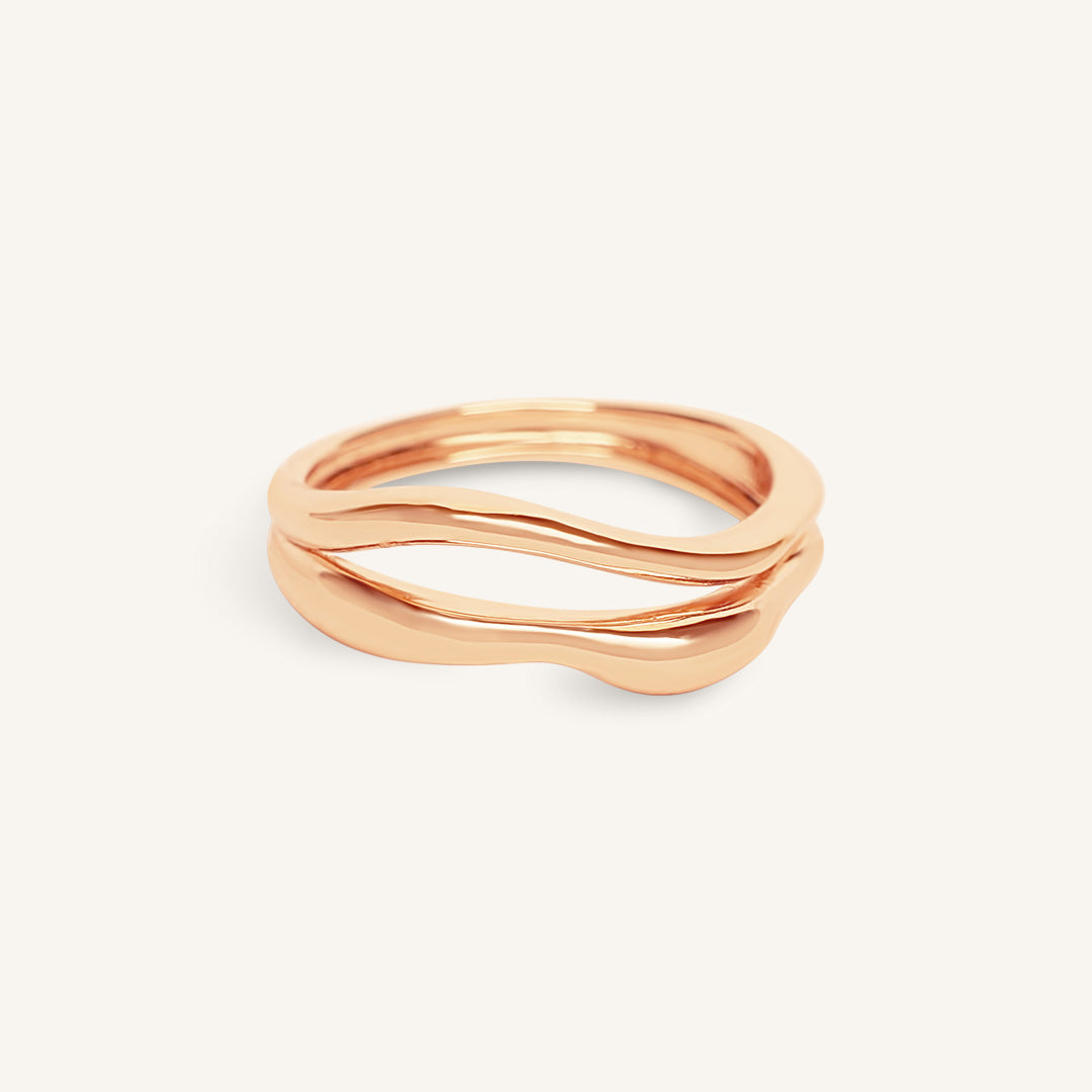 Rose gold ring with wavy design on a white background