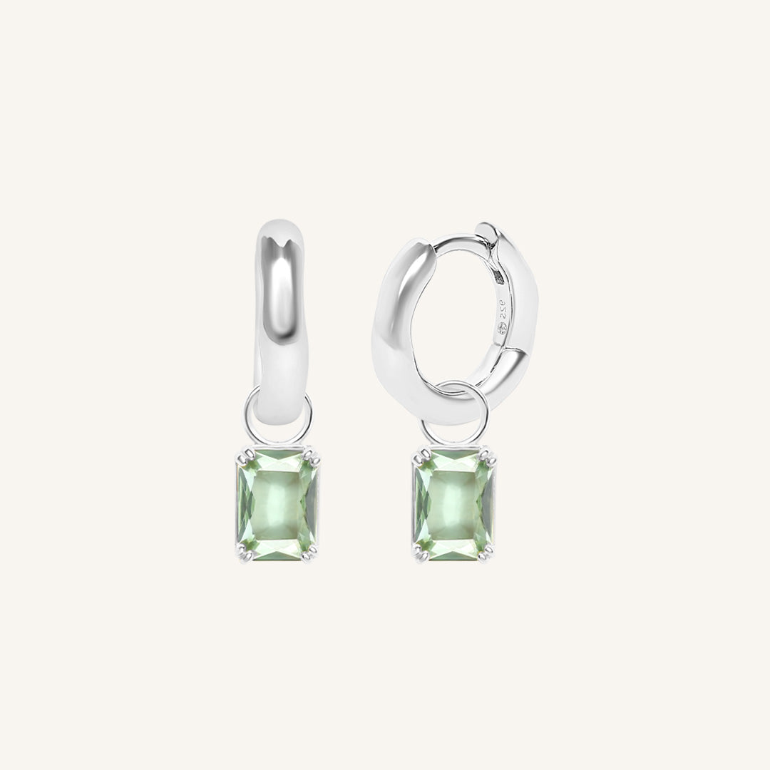 Pair of silver earrings with green gemstones on a white background