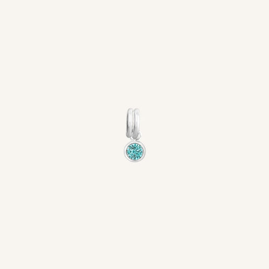 Round silver charm with bezel-set turquoise cubic zirconia representing the December birthstone