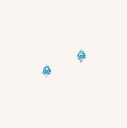 A silver pair of stud earrings featuring a blue cubic zirconia, representing December.