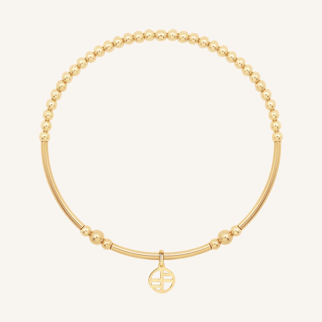Gold bracelet with a small round charm on a white background