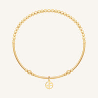 Gold bracelet with a small round charm on a white background