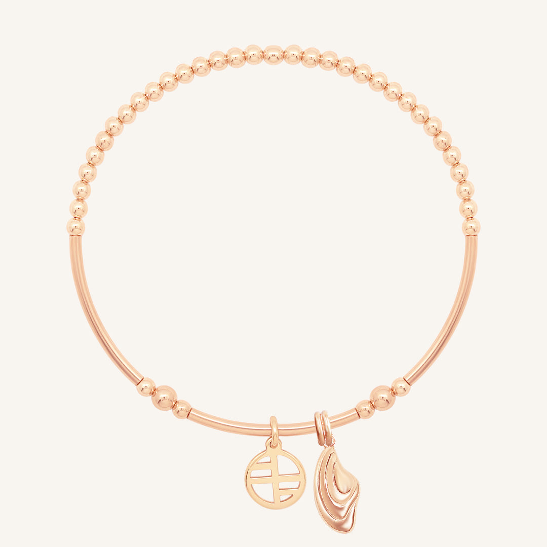 Rose gold bracelet with two charms on a white background