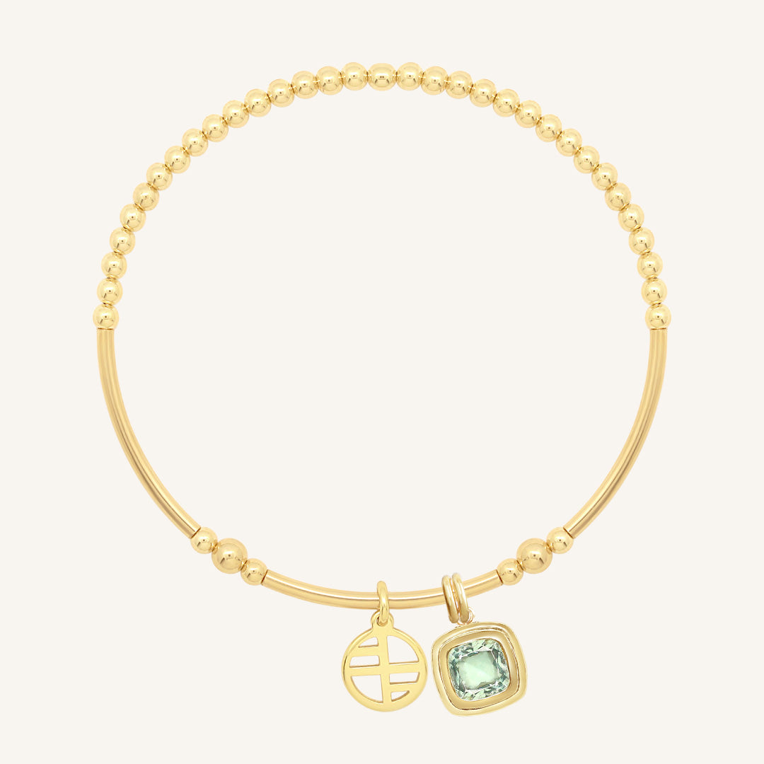Gold bracelet with a green gemstone charm on a white background