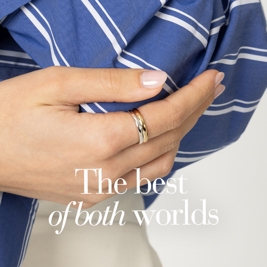 Hand wearing a two tone, mixed metal ring and a blue and white striped shirt