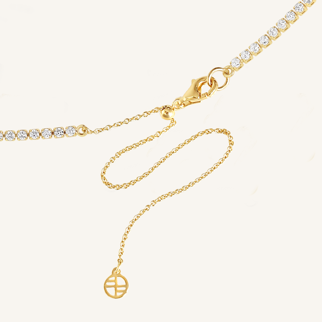 Close up of clasp on tennis chain necklace with gold metal tone.