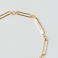 A silver chain bracelet with an adjustable fastening design and an engraveable panel.