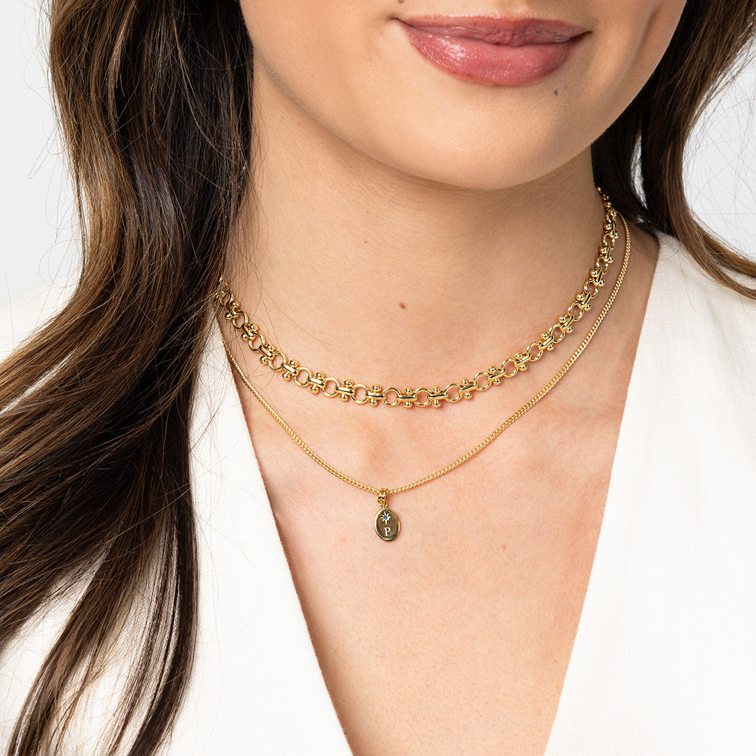 Close-up of a person wearing two gold necklaces on a white background