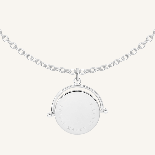 A silver-coloured, engraved pendant with, featuring a spinning mechanism, on chain