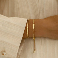 A gold chain bracelet with an adjustable fastening design and an engraveable panel.