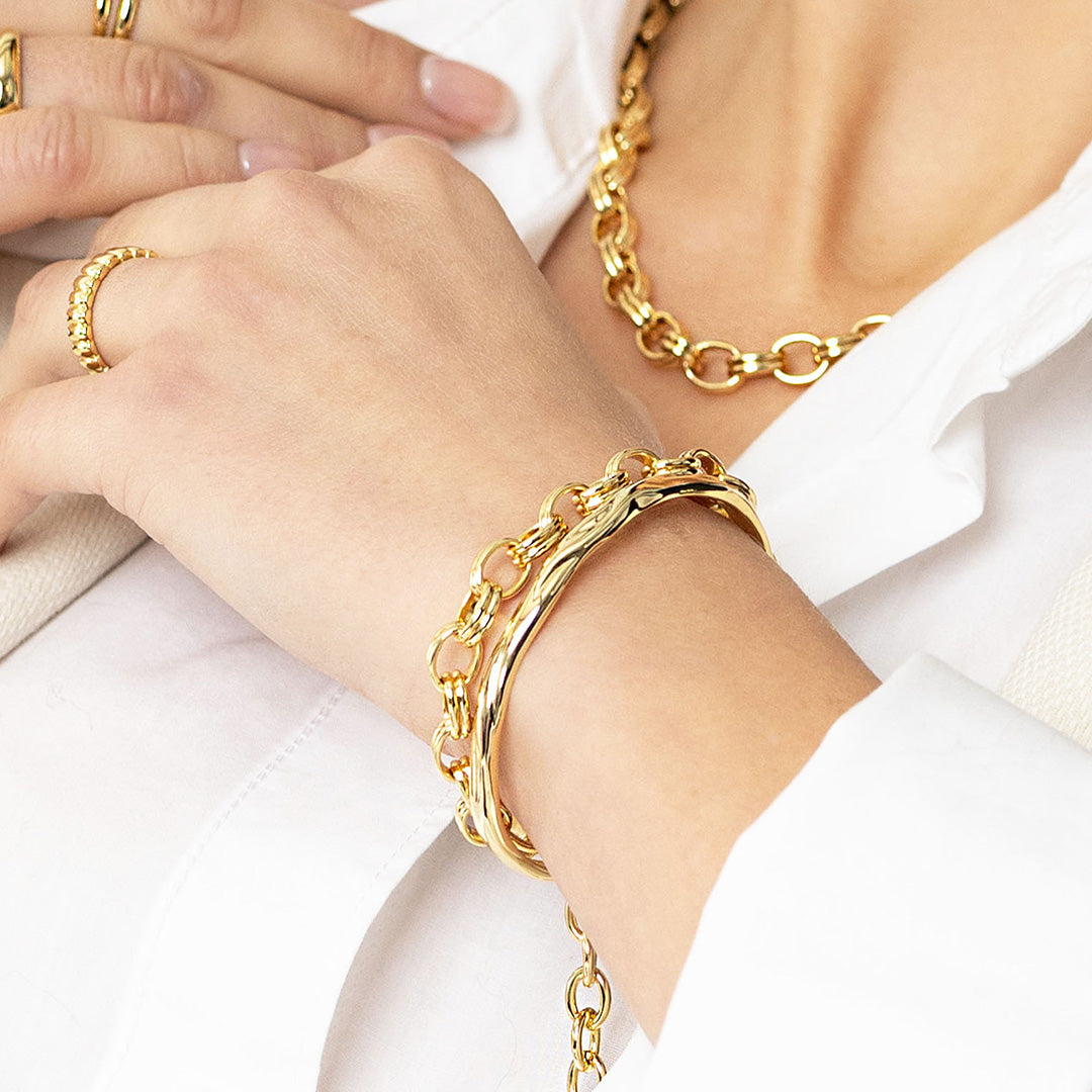 Gold chain bracelet on a wrist with a white shirt background
