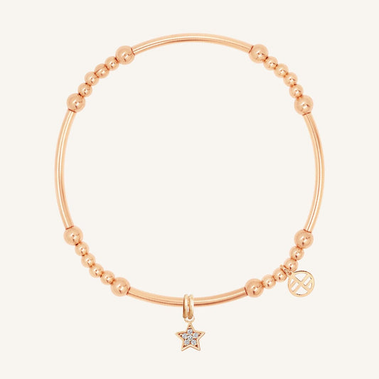 A rose gold-coloured bracelet with a luck star charm and small bead details.