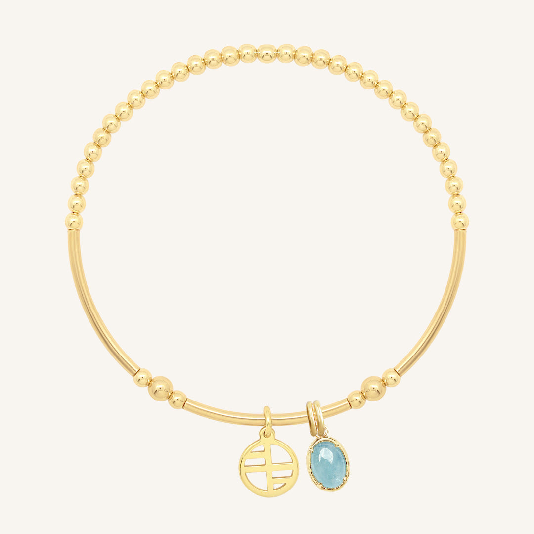 Gold bracelet with a blue gemstone charm on a white background
