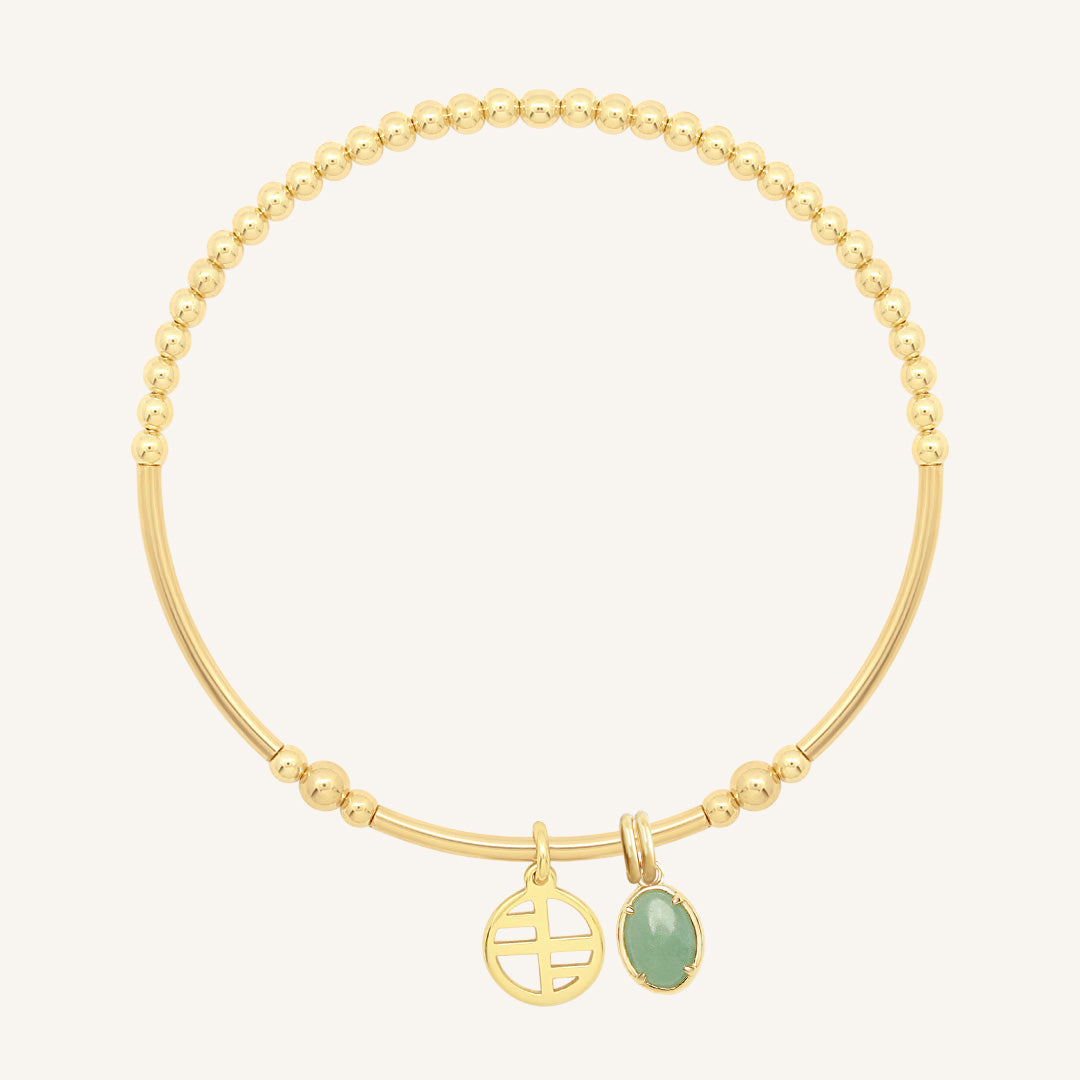 Gold bracelet with a greenstone charm on a white background