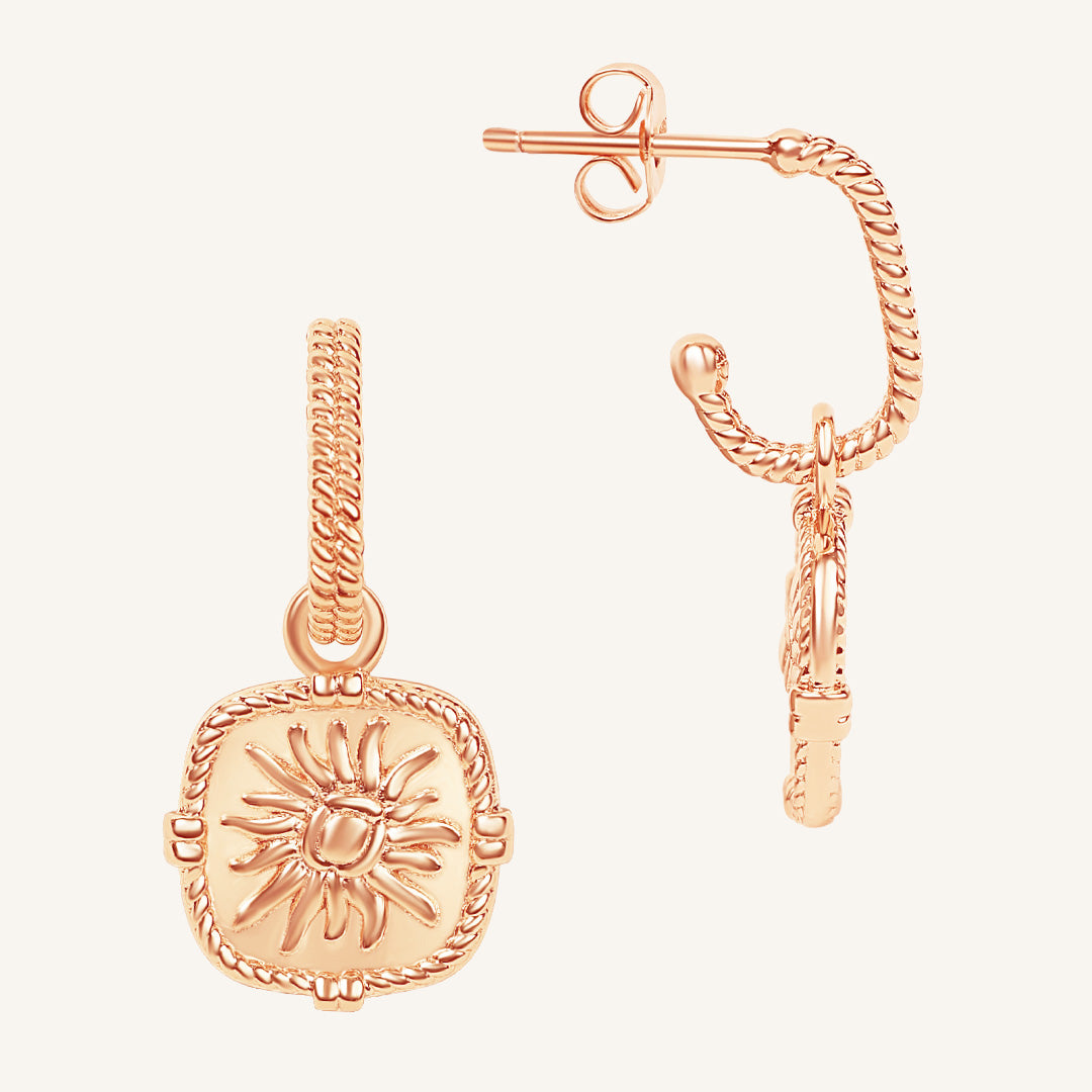 Rose gold sun-shaped pendant earring on a white background