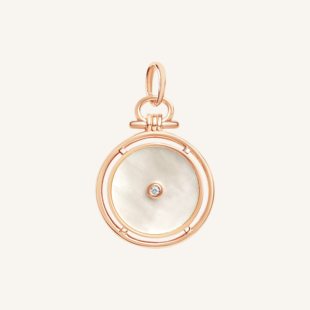Rose gold pendant with a white circular face and central gemstone on a light beige background