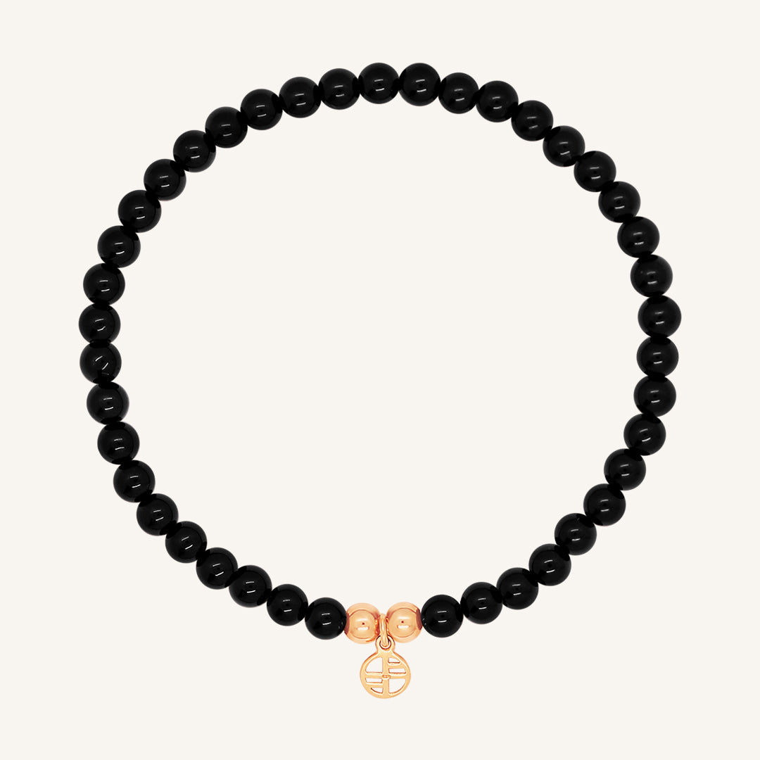 A black beaded bracelet made of black agate stones with a rose charm, displayed against a white background.