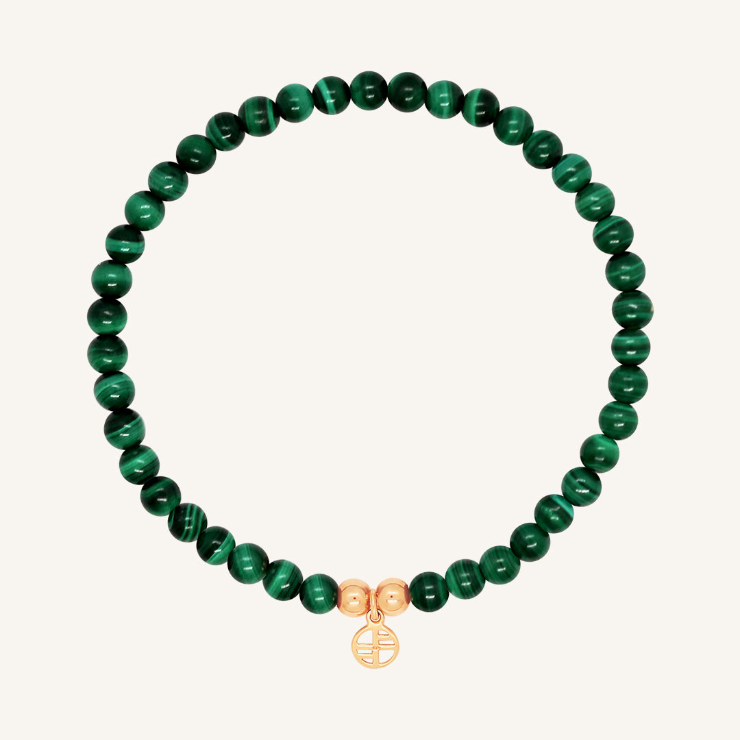 A beaded bracelet made of green malachite stones and metal beads with a rose-colored charm, displayed on a white background.
