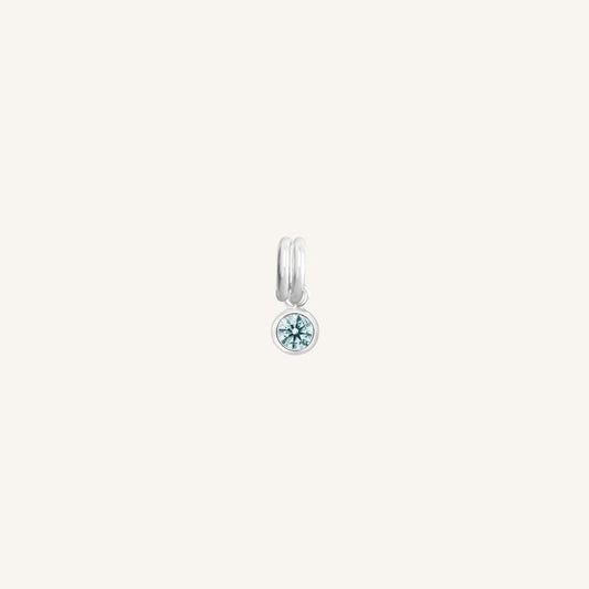 Round silver charm with bezel-set aquamarine cubic zirconia representing the March birthstone.