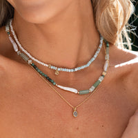 Gold pendant with a blue stone on a white background