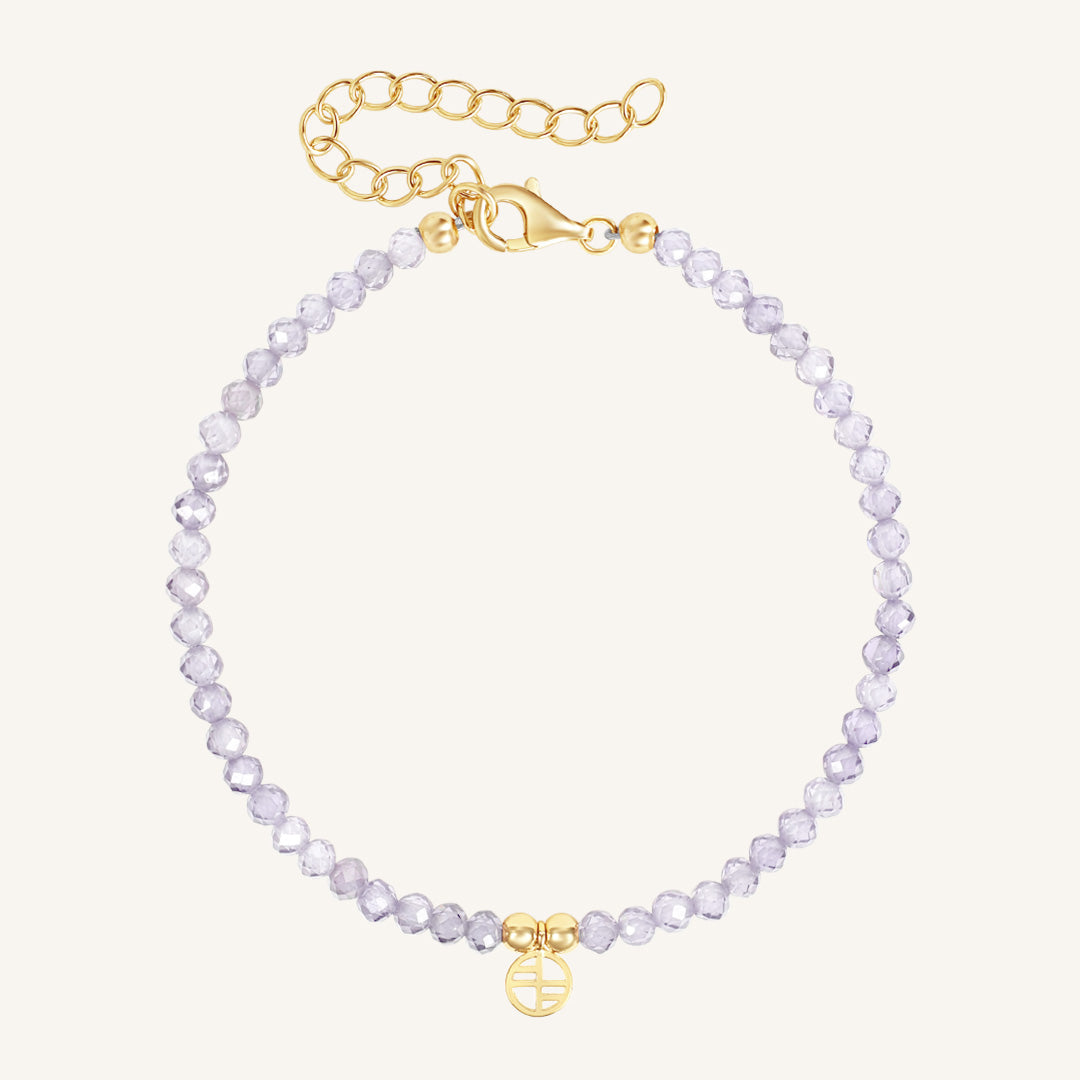 Bracelet with light purple beads and gold clasp on a white background