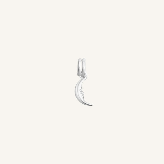 A silver charm in the shape of a crescent moon