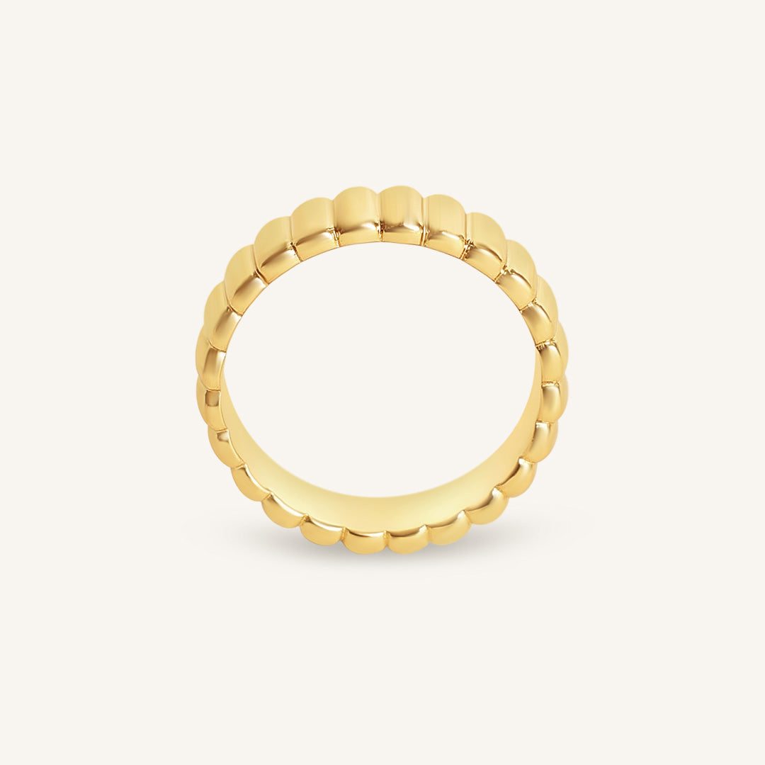 Gold ring with a textured band on a white background