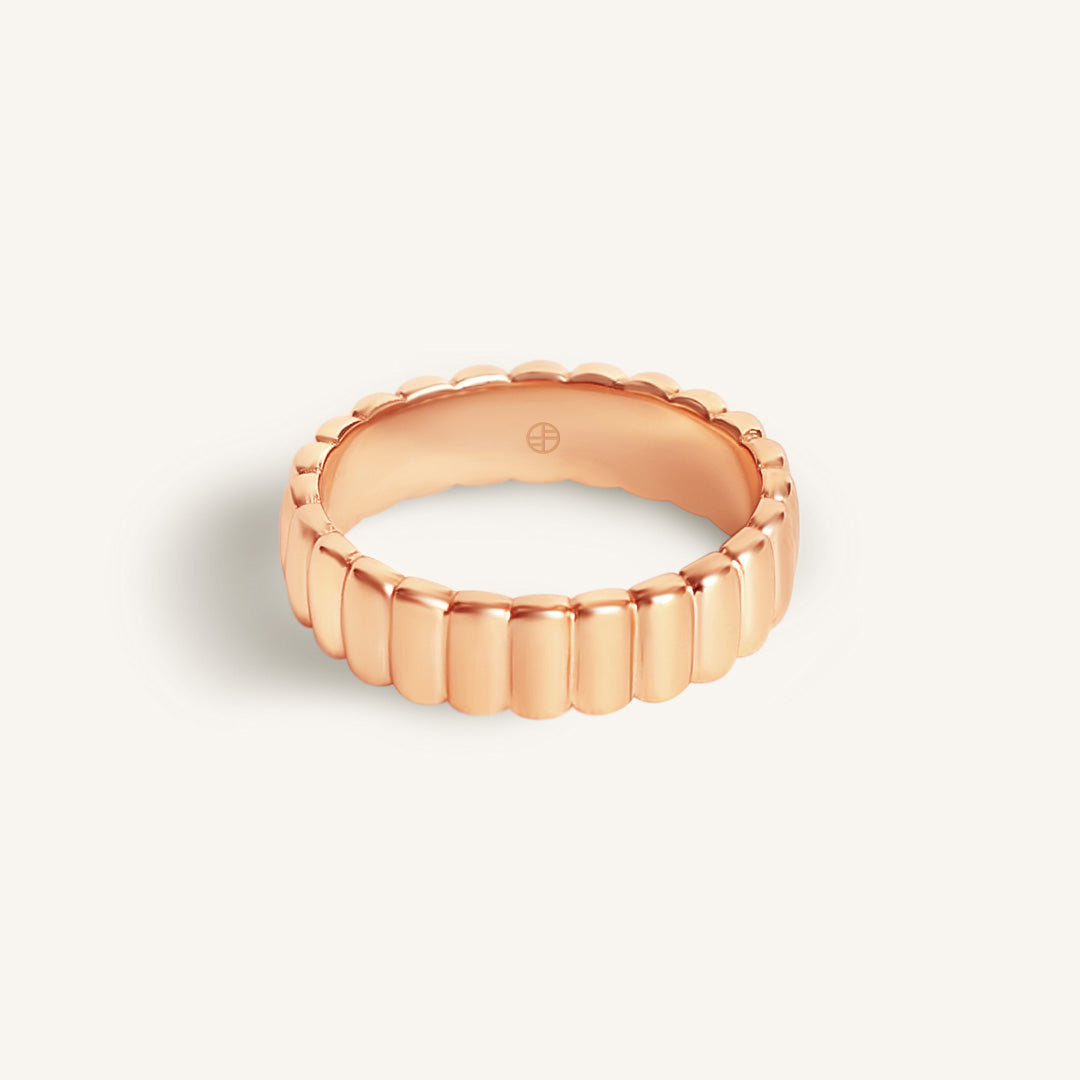 Rose gold ring with a textured band on a light beige background