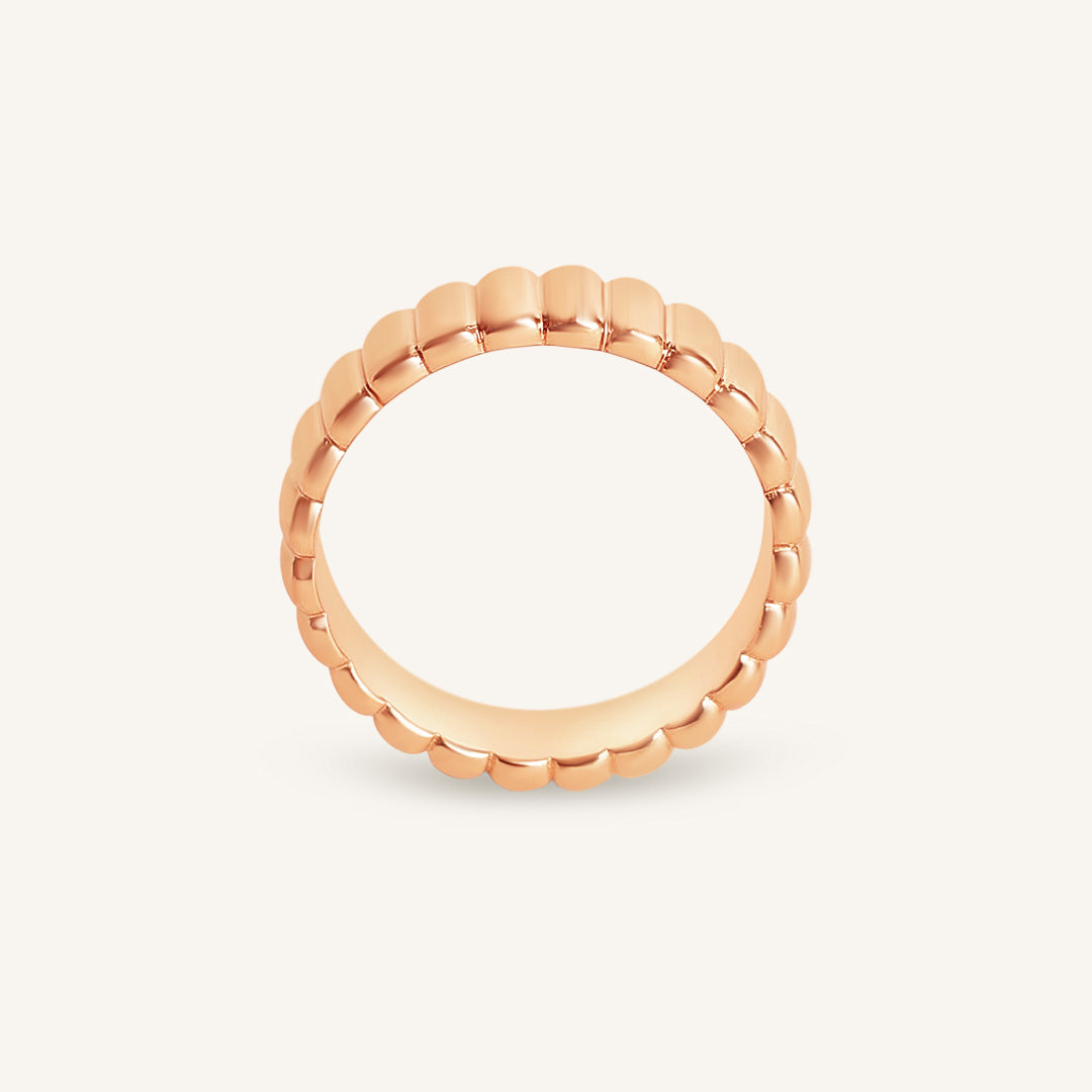 Rose gold ring with a textured band on a light gray background