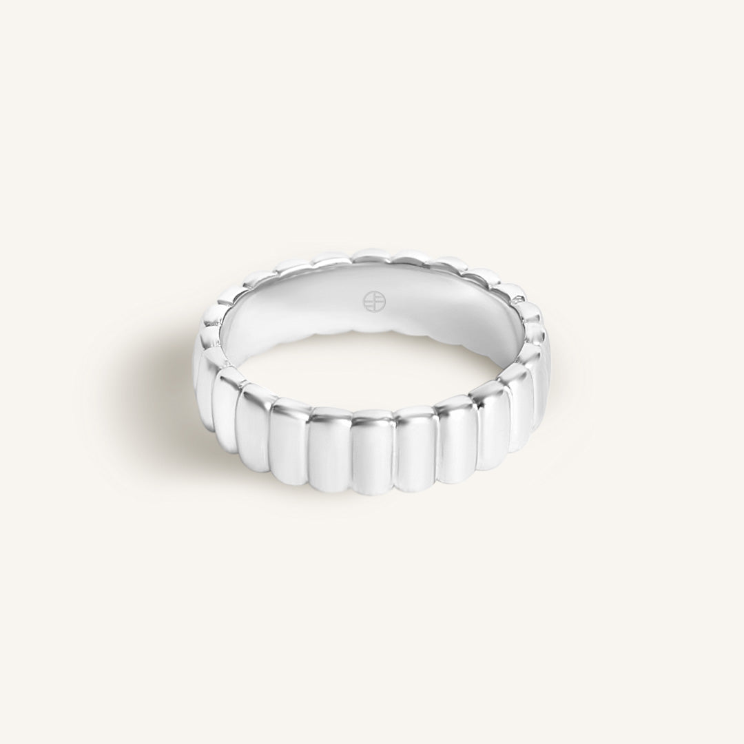 Silver ring with a textured band on a white background